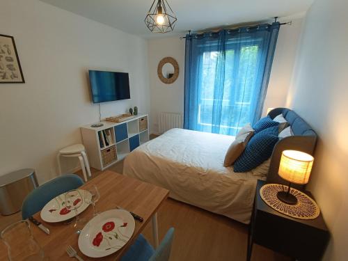 a bedroom with a bed and a table and a dining room at Studio Cosy neuf + lit bébé à 4 minutes RER A in Montévrain