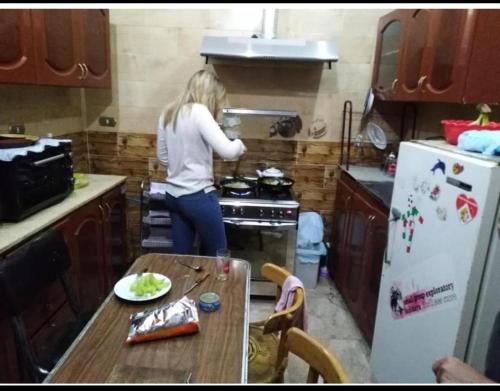 a woman standing in a kitchen cooking in a stove at NUBA ONe in Aswan