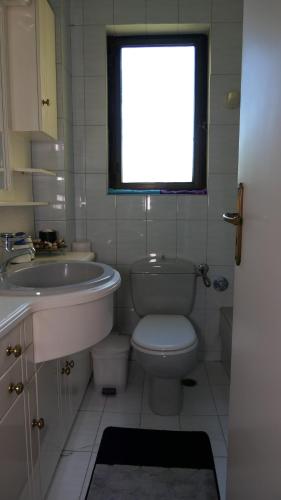 baño con aseo y lavabo y ventana en Ioanna's Elegant Residence, Agia Paraskevi, en Atenas