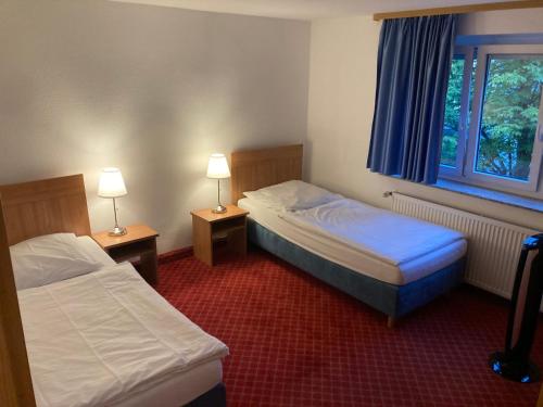 a hotel room with two beds and a window at Hotel Schillerplatz in Öhringen