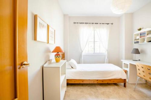 um quarto com uma cama, uma secretária e uma janela em La casa de Marilo em Tomares