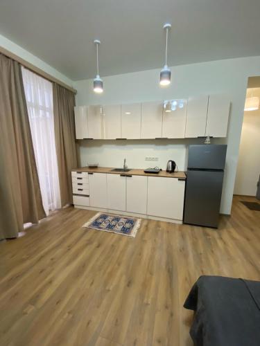 a kitchen with white cabinets and a black refrigerator at Tbilisi cozy apartment in Tbilisi City
