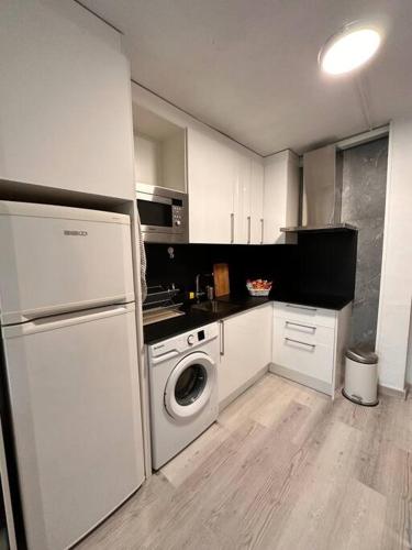 a kitchen with white cabinets and a washing machine at A pie de PLAYA in La Pineda