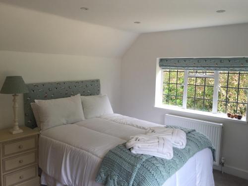 a bedroom with a bed with white sheets and a window at Middle Wymson House in Stratford-upon-Avon