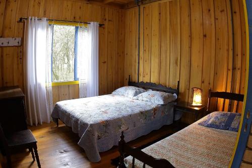 a bedroom with two beds and a window at Chalé Morada Alma Gêmea in Campo Alegre