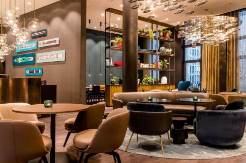 a restaurant with tables and chairs and chandeliers at Motel One Köln-Altstadt in Cologne