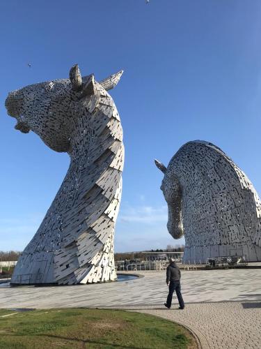 a man walks past two large metal sculptures of horses at Scardroy Falkirk - Central 3 Bedroom Apartment with Parking, WiFi, Smart TVs in Falkirk