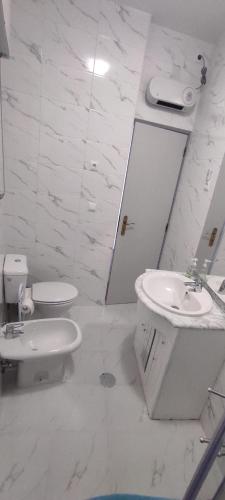 a white bathroom with a sink and a toilet at Casa Viela in Viseu