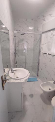 a white bathroom with a sink and a shower at Casa Viela in Viseu
