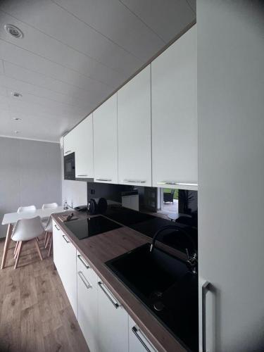 a kitchen with white cabinets and a black counter top at Apartament Holiday in Dąbki