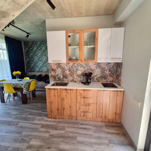 a kitchen with wooden cabinets and a table with yellow chairs at Gina Apartments in Shekvetili