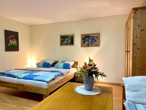 ein Schlafzimmer mit einem Bett und einer Vase aus Blumen auf einem Tisch in der Unterkunft Bayerischer Wald - Balbersdorf in Waffenbrunn