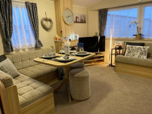 a living room with a table and a couch at Comfy Cosy Caravan_Romney Sands in Littlestone-on-Sea