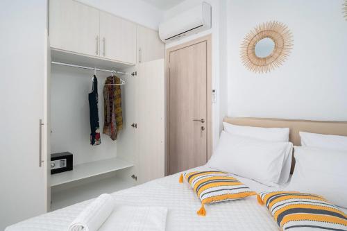 a bedroom with a bed with white walls and a mirror at Amersa Luxury Apartment in Néa Alikarnassós