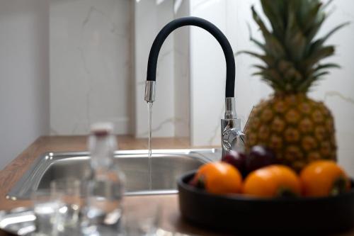 a sink with a bowl of fruit next to a pineapple at Amersa Luxury Apartment in Néa Alikarnassós