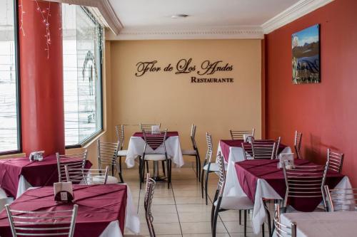 un restaurante con paredes rojas, mesas y sillas en HOTEL FLOR DE LOS ANDES en Tulcán