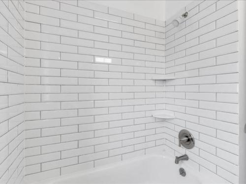 a white tiled bathroom with a toilet in it at Quaint 3/2.5 home in Fort Dupont in Washington