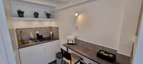 une cuisine avec un évier et un comptoir avec des chaises dans l'établissement Le Studio de Véra - Intra Muros - Wifi, à Avignon