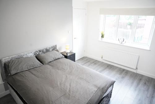 a white bedroom with a large bed and a window at Ricoh Arena/Newly Refurbished Semi-Detached House in Exhall