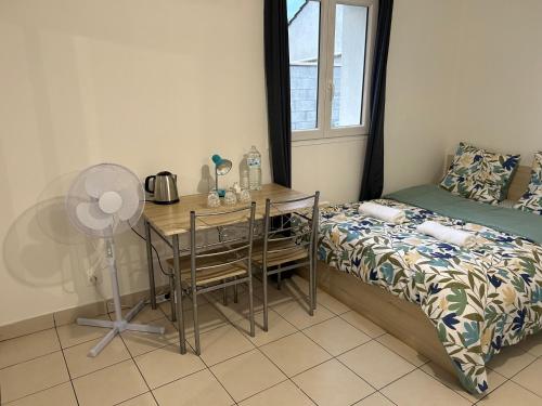 Schlafzimmer mit einem Tisch, einem Bett und einem Ventilator in der Unterkunft L'idéal séjour avec jardin privé proche Paris gare et commerce in Sarcelles