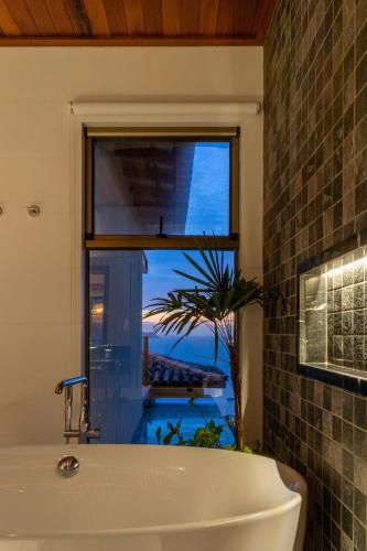 a bathroom with a tub and a window with a view at Casa Mirador Boutique Hotel in Búzios
