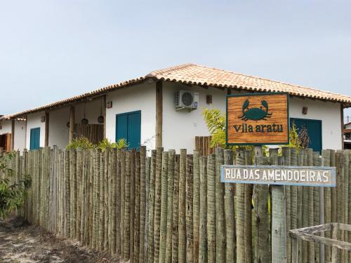 a fence in front of a house with a sign at Vila Aratu Corumbau in Corumbau