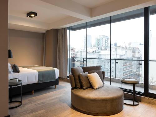 Habitación de hotel con cama, silla y ventana grande. en Casa Joseph en Buenos Aires