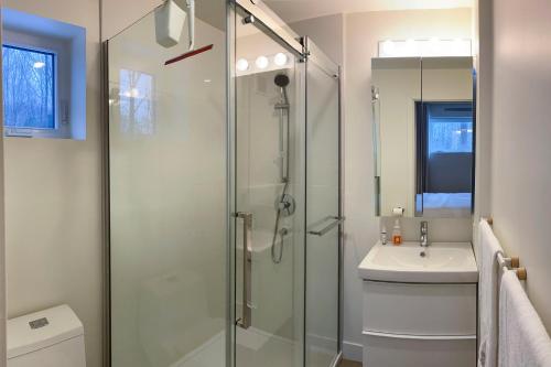 a bathroom with a glass shower and a sink at Le Camp Caché Shefford in Shefford