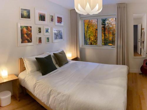 a bedroom with a large white bed and a window at Le Camp Caché Shefford in Shefford