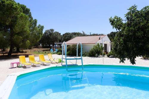 a swimming pool with chairs and a house at Monte dos Abrunhos in Vimieiro