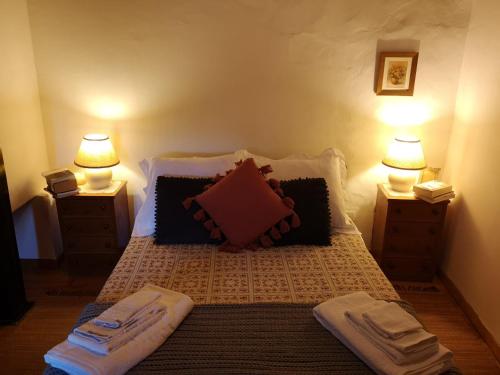 Toca do Esquilo - Montesinho في Montezinho: غرفة نوم فيها سرير وعليها مصابيح ومناشف