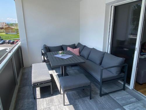 einen Tisch und Stühle sowie ein Sofa auf dem Balkon in der Unterkunft Wunderschöne, neue Wohnung mit großer Terrasse in Ebenthal