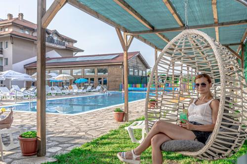 a woman sitting in a chair next to a pool at Thermal Hotel Seven Seasons in Banya