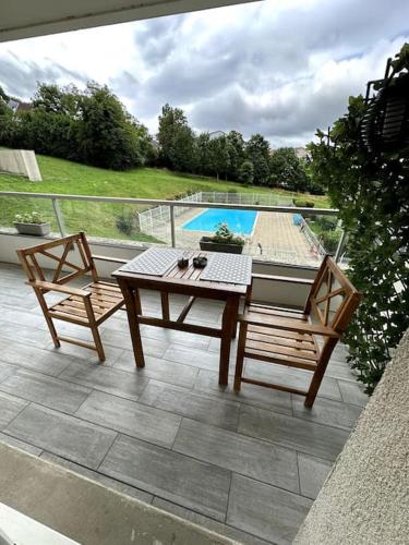 une terrasse avec une table et deux chaises ainsi qu'une piscine dans l'établissement Appartement cosy avec balcon et piscine, à Besançon