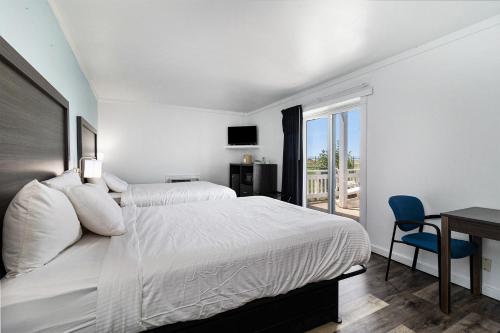 - une chambre blanche avec un lit, un bureau et une fenêtre dans l'établissement Snyders Shoreline Inn, à Ludington