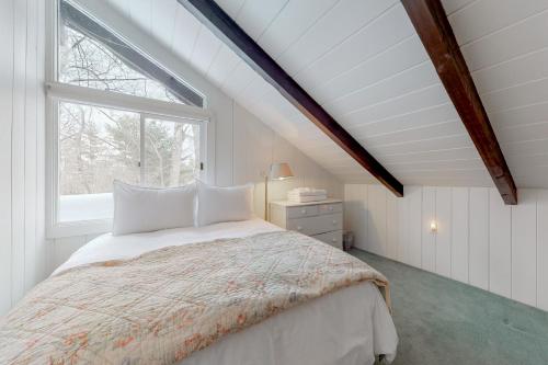 a white bedroom with a bed and a window at Chalet at Shawnee in Bridgton