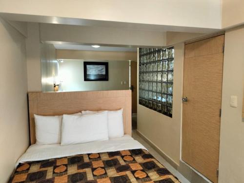 Dormitorio pequeño con cama con almohadas blancas en Hotel y Aguas Termales de Chignahuapan, en Chignahuapan