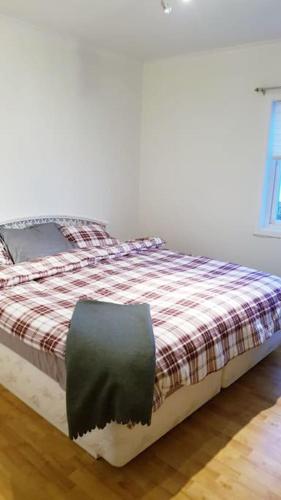 a bedroom with a bed with a checkered blanket at Koselig leilighet med balkong og parkering. in Stavanger