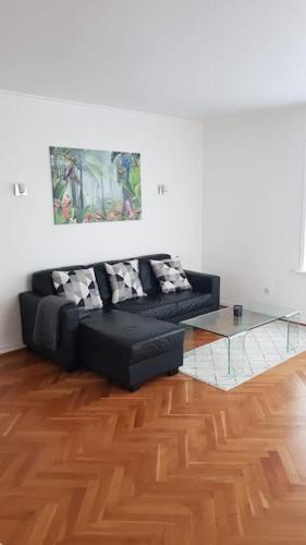 ein Wohnzimmer mit einem schwarzen Sofa und einem Glastisch in der Unterkunft Koselig leilighet med balkong og parkering. in Stavanger