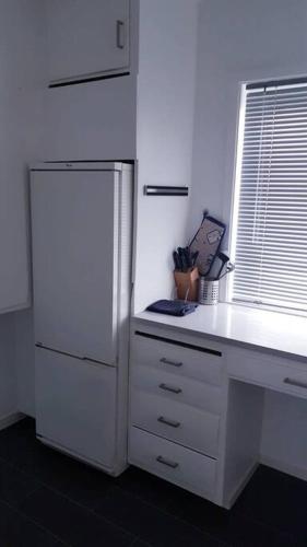 a kitchen with a white desk and a refrigerator at Koselig leilighet med balkong og parkering. in Stavanger