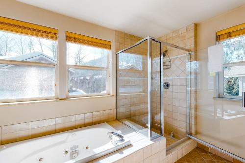 a bathroom with a tub and a shower and windows at Sun Bird Getaway at River Run in Ketchum