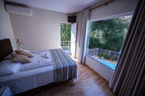 1 dormitorio con cama y ventana grande en Cachoeira dos pássaros, en Foz do Iguaçu