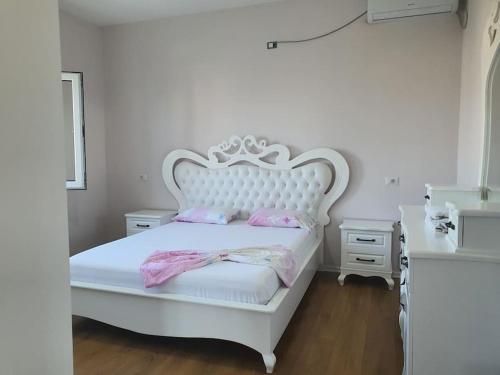 a white bedroom with a white bed with pink pillows at Green Villa in Durrës