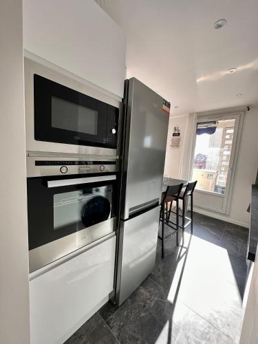 une cuisine avec un réfrigérateur en acier inoxydable et un micro-ondes dans l'établissement Appartement 3 chambres - Proche metro, à Villeurbanne