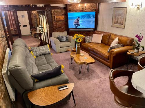 - un salon avec des canapés en cuir et une télévision dans l'établissement Cathedral View, à Gloucester
