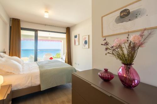 um quarto com uma cama e um vaso com flores sobre uma mesa em Appart Florida Mer 3ch Luxe em Schœlcher