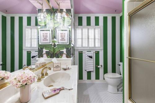 La salle de bains est pourvue d'un lavabo, de toilettes et de rayures vertes et blanches. dans l'établissement Pink Shutter House, à Conroe