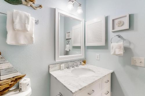 La salle de bains blanche est pourvue d'un lavabo et d'un miroir. dans l'établissement Baywatch F4, à Pensacola Beach