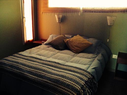 1 cama no hecha en un dormitorio con ventana en La Reserva en el Mar en Puerto Pirámides