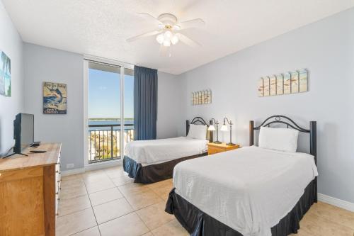 ein Hotelzimmer mit zwei Betten und einem Fernseher in der Unterkunft Beach Colony Resort West 10F in Navarre